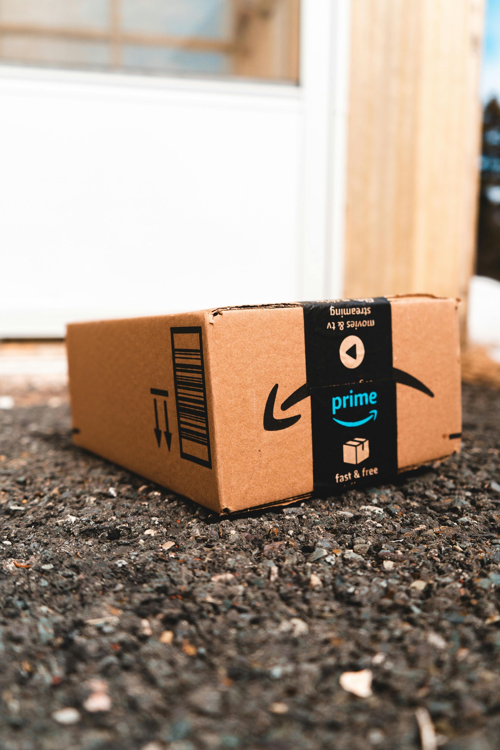An amazon prime box is sitting on the ground in front of a door.