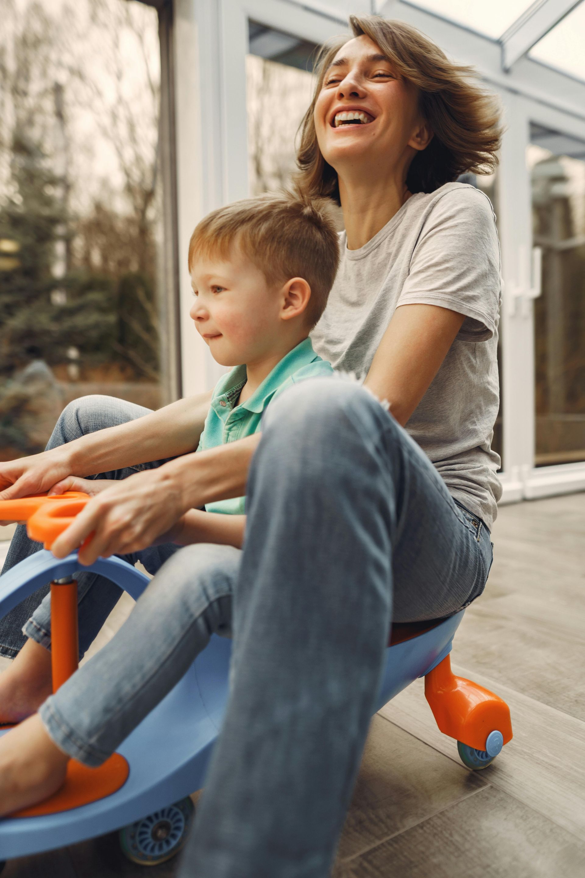 A woman and a child are sitting on a toy car.