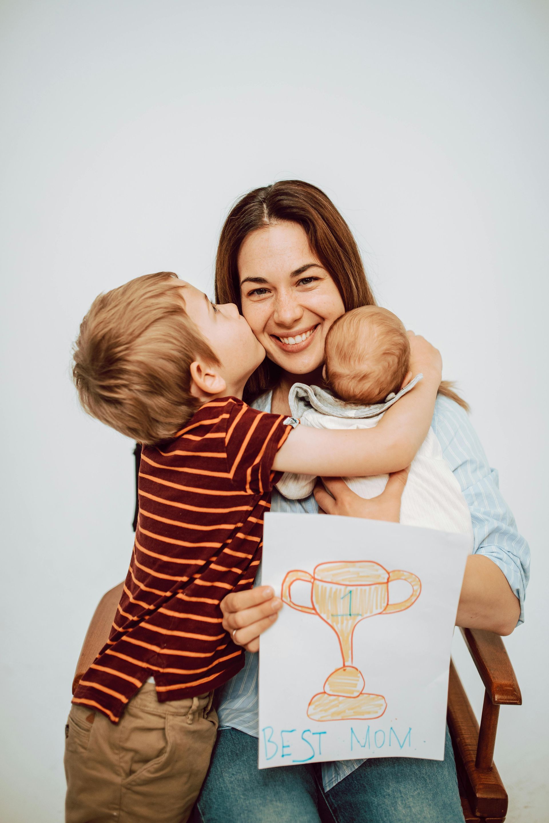 A woman is holding a baby and a drawing of a trophy.