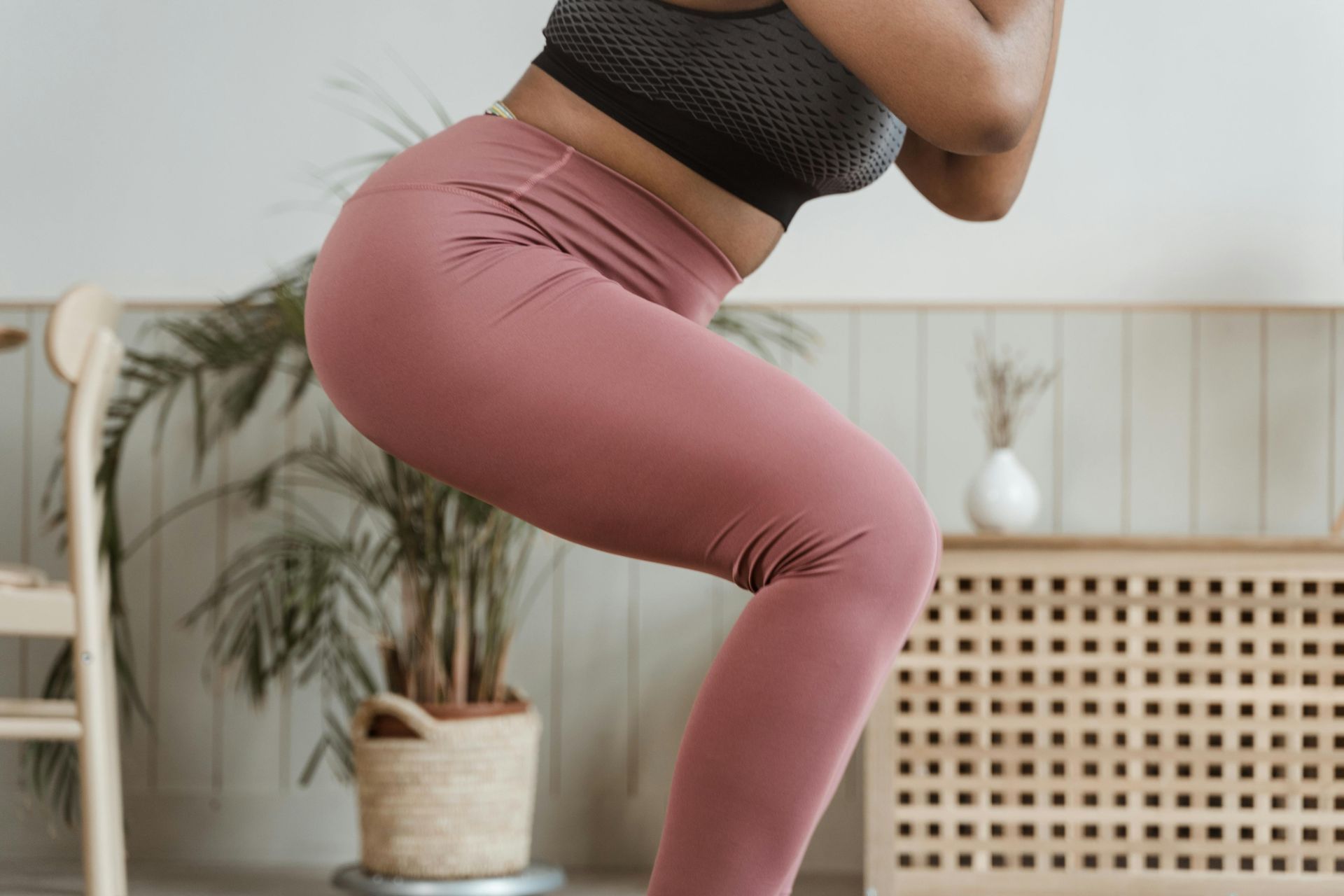 Woman in pink leggings doing a squat indoors.