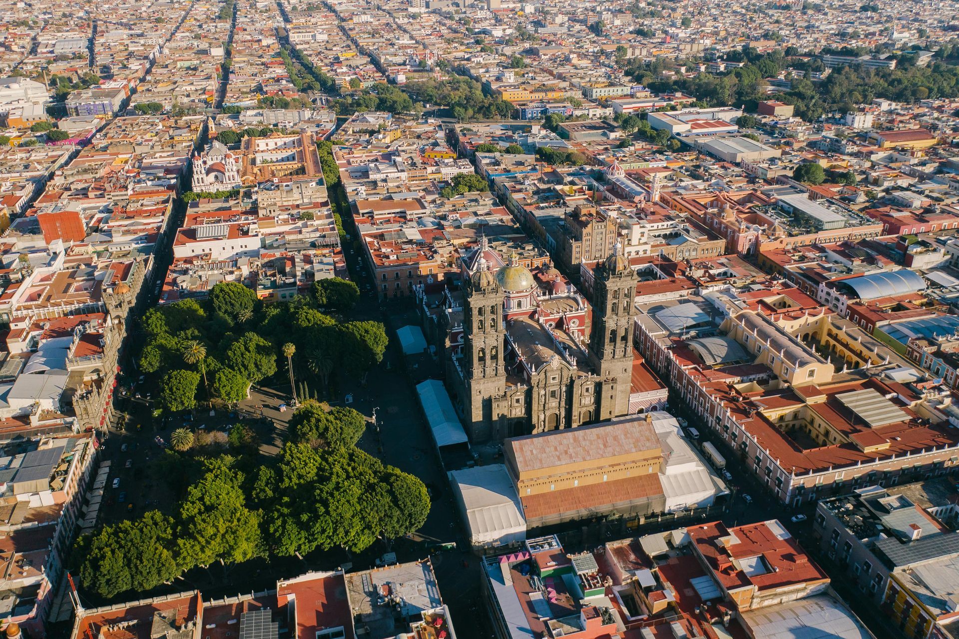 Aerial view of a city with a cathedral and park; buildings and streets form a grid pattern.