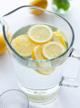 A pitcher of water with lemon slices in it.