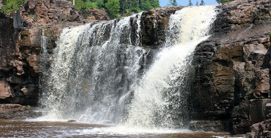 A waterfall is surrounded by rocks and trees in the middle of a forest.