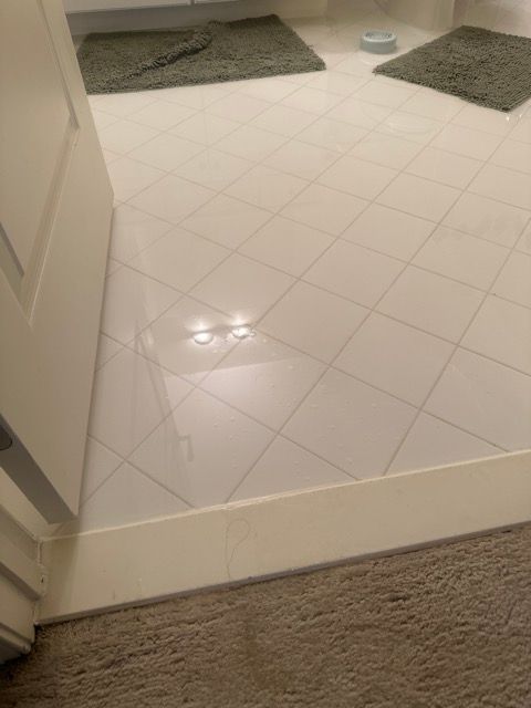 A bathroom with a white tile floor and a carpeted floor.