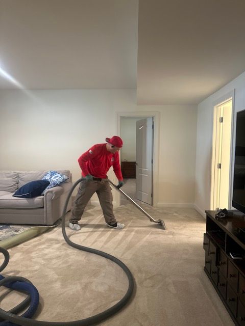 A man is vacuuming a carpet in a living room