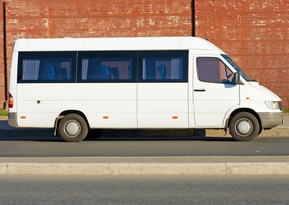 White Passenger Van Parked Next to a Red Brick Wall — Mission Truck Training in Mountain Creek, QLD
