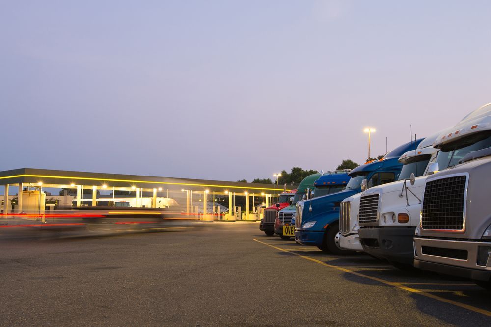 Semi-Trucks Parked at a Truck Stop at Dusk, With a Blurred Car Passing by — Mission Truck Training in Maroochydore, QLD