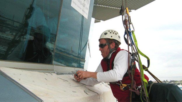 man working on windows with harness on
