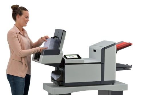 A woman is standing next to a large printer.