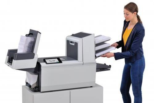 A woman is putting papers into a printer.