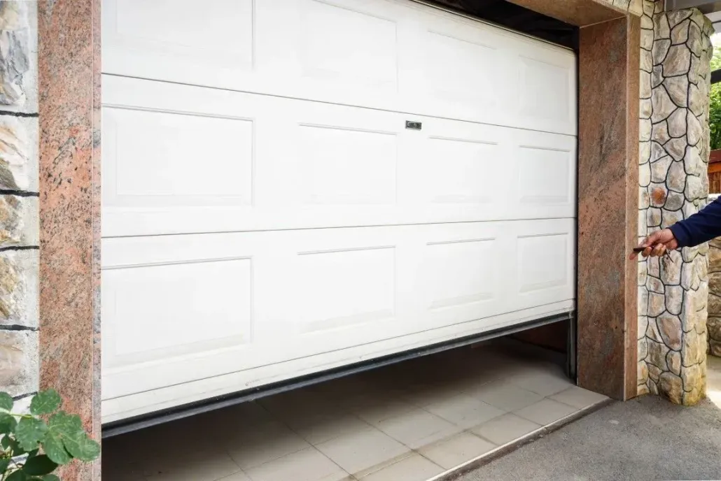 Garage door technician installing a white sectional door on a modern home.