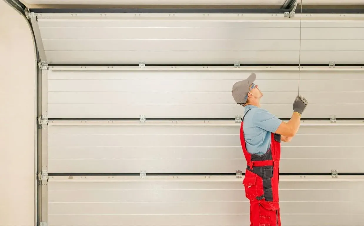 Professional installer aligning panels during a new garage door installation.
