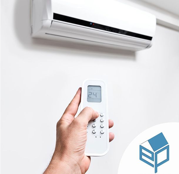 Una mano impugna un telecomando puntato verso un condizionatore d'aria bianco montato a parete.