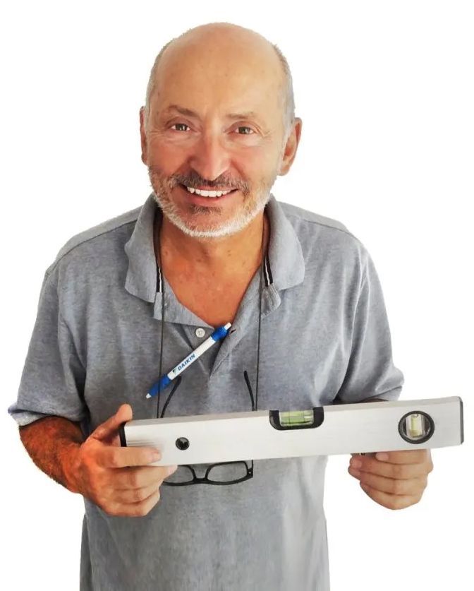 Una persona sorridente con indosso una polo grigia tiene in posizione orizzontale una livella a bolla d'argento.