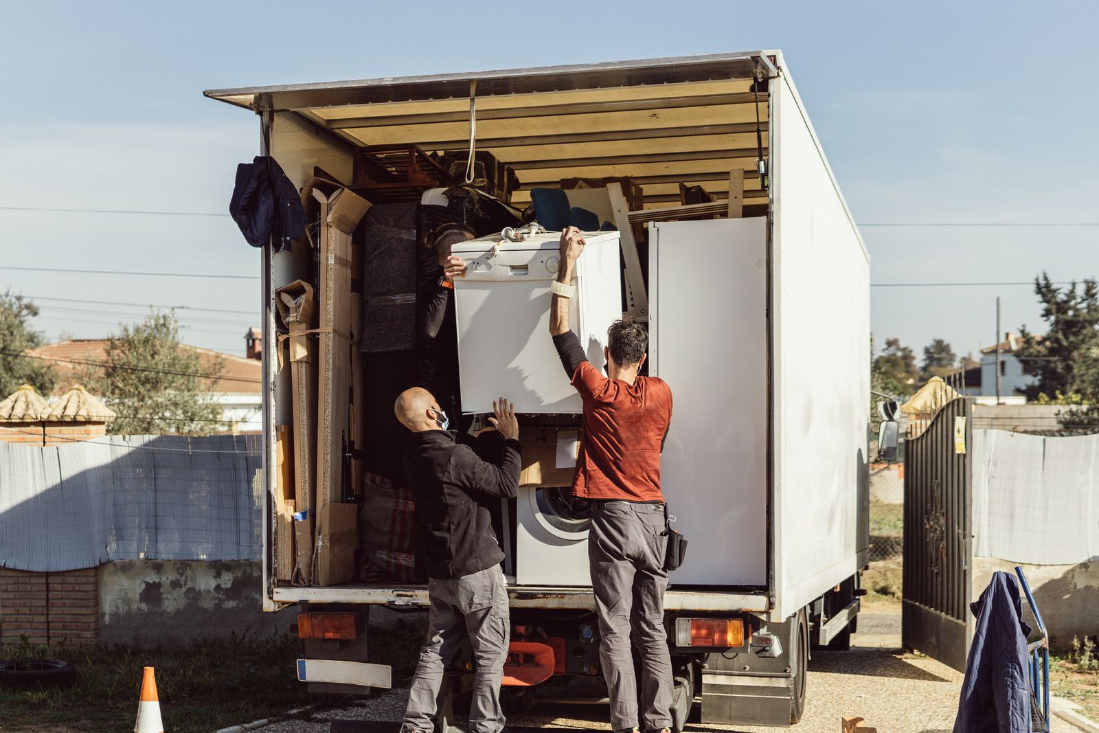 Two men are loading appliances into a moving truck.