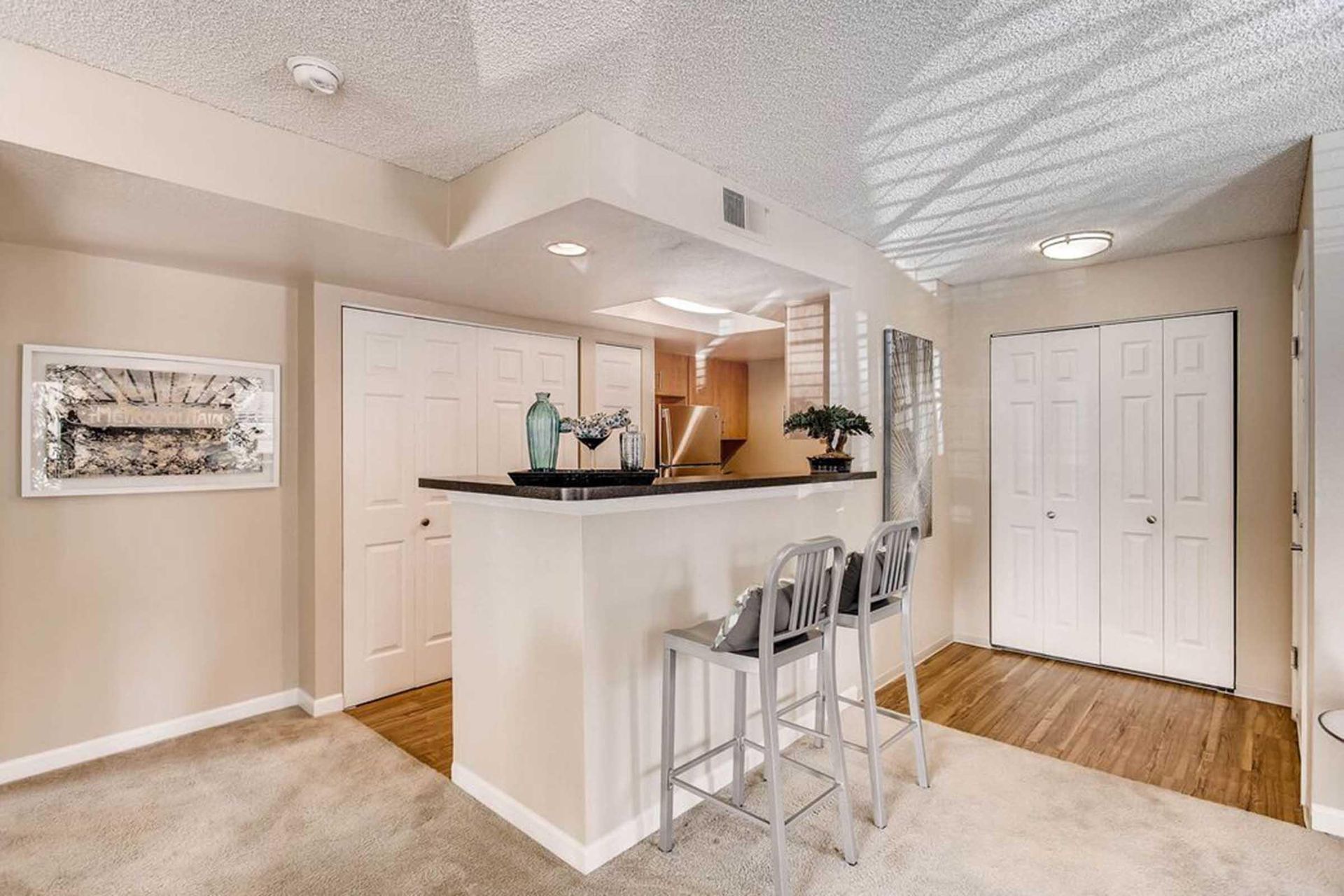 Interior view of a kitchen bar with stools, beige walls, and white cabinets at Chestnut Ridge Apartment Homes, offers apartments in Denver, CO.