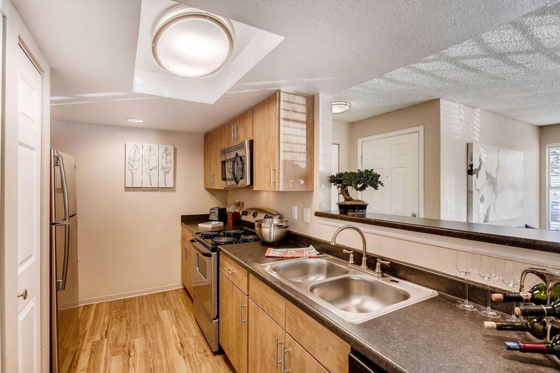 Kitchen with light-colored cabinets, stainless steel appliances, dark countertops, and a pass-through to another room at Chestnut Ridge Apartment Homes, offers apartments in Denver, CO.