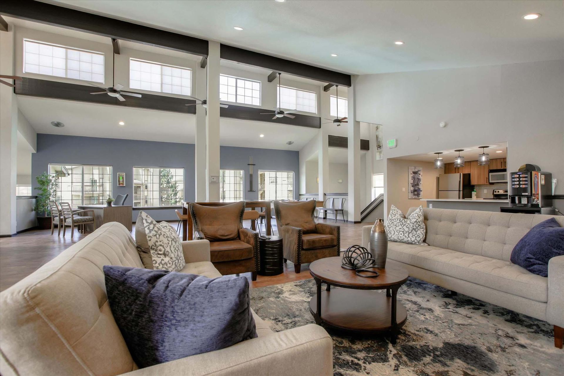 Clubhouse with couches, chairs, coffee table, and kitchen in an apartment community at Chestnut Ridge Apartment Homes, offers apartments for rent in Denver, CO.