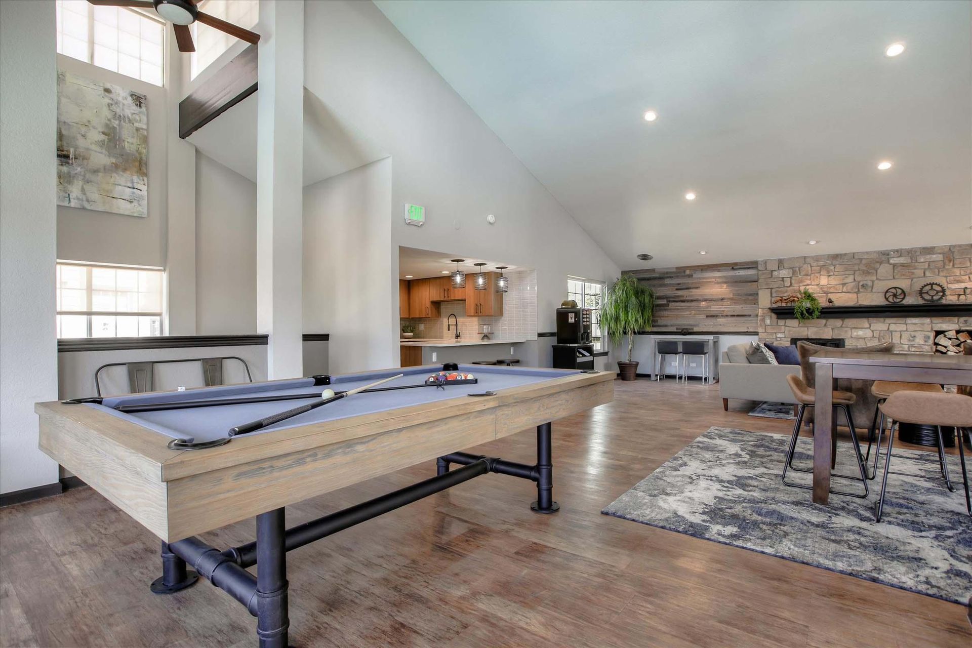 Pool table in a spacious rec room with high ceilings, fireplace, and kitchen area at Chestnut Ridge Apartment Homes, offers apartments for rent in Denver, CO.