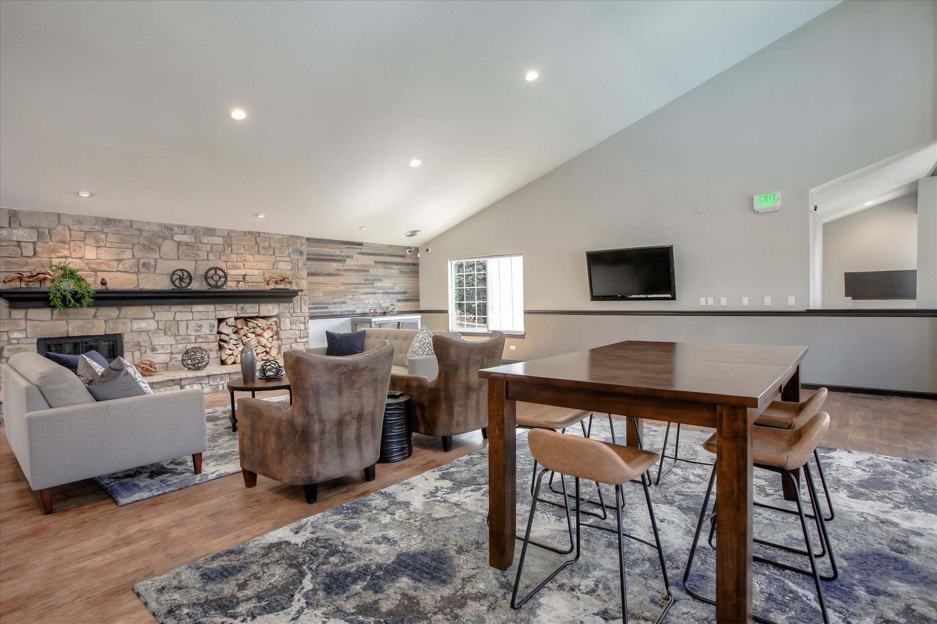 Cozy lounge with fireplace, chairs, table, and TV. Stone wall, wooden floor, and a rug at Chestnut Ridge Apartment Homes, offers pet-friendly apartments for rent in Denver, CO.