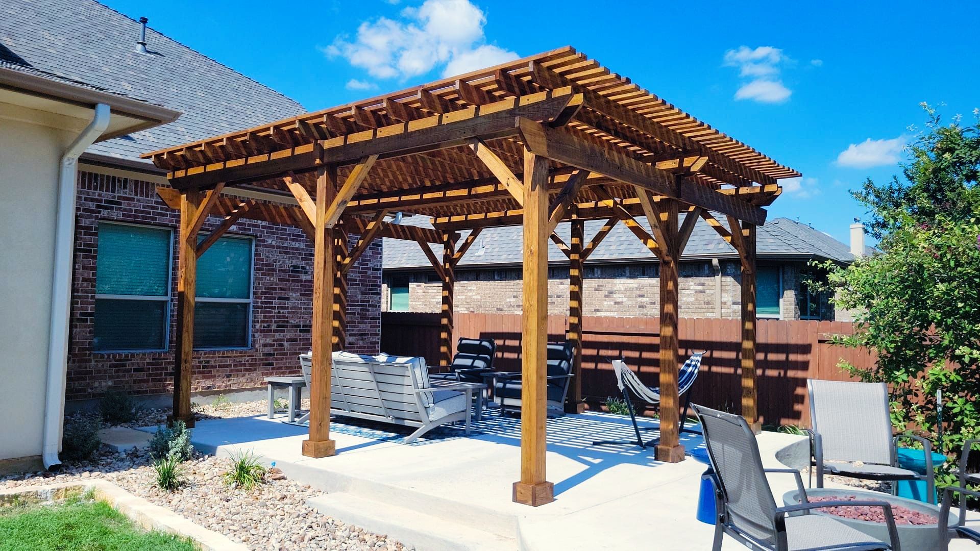 There is a wooden pergola in the backyard of a house.