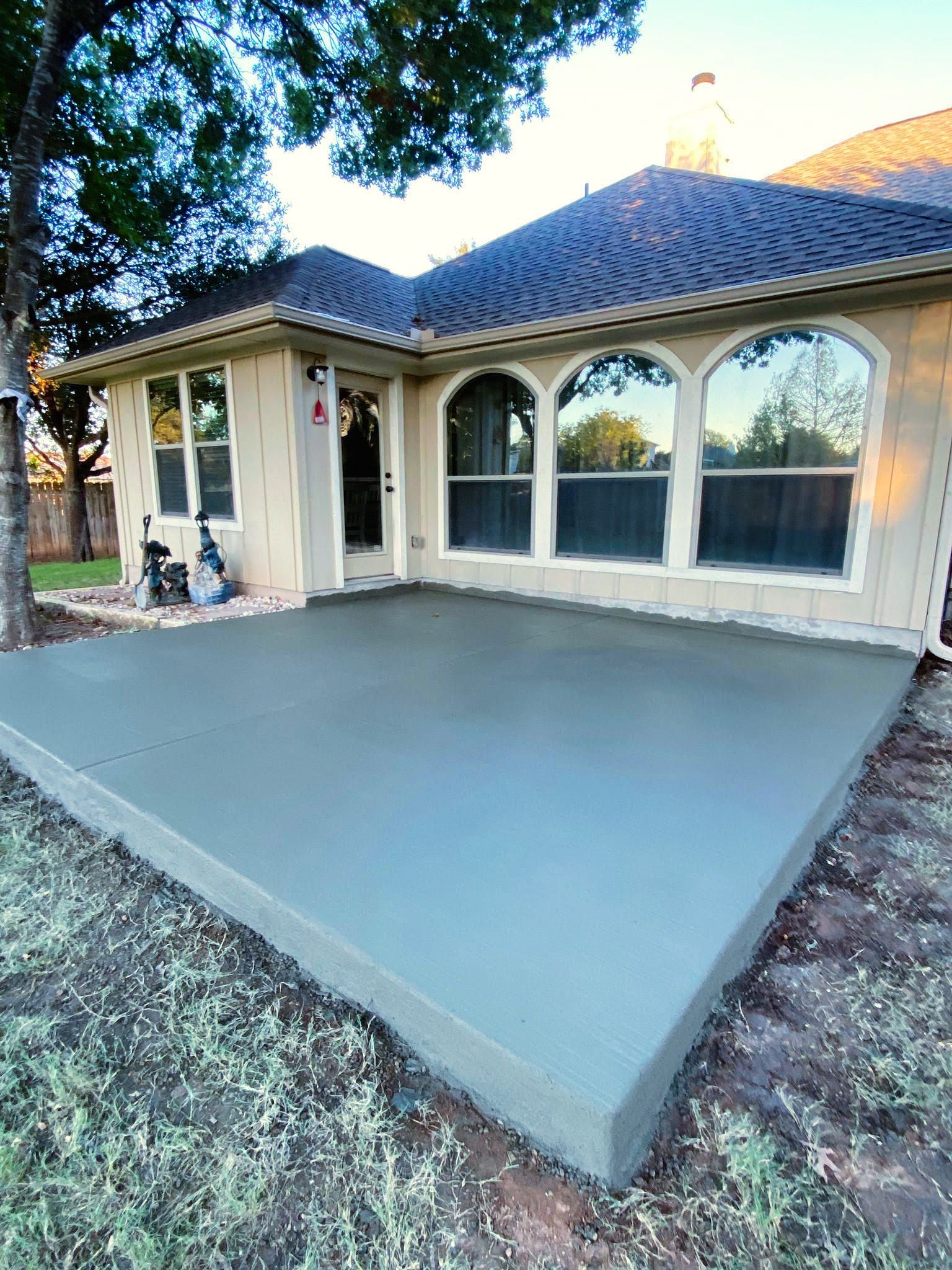 A concrete patio is being built in front of a house.