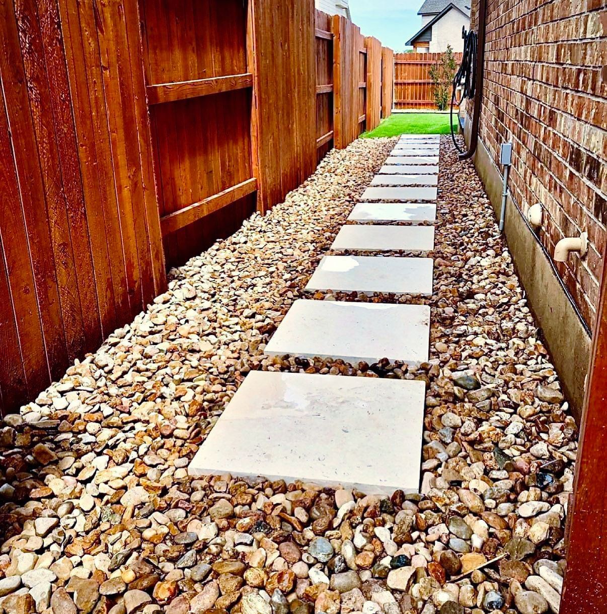 A stone walkway with a wooden fence in the background