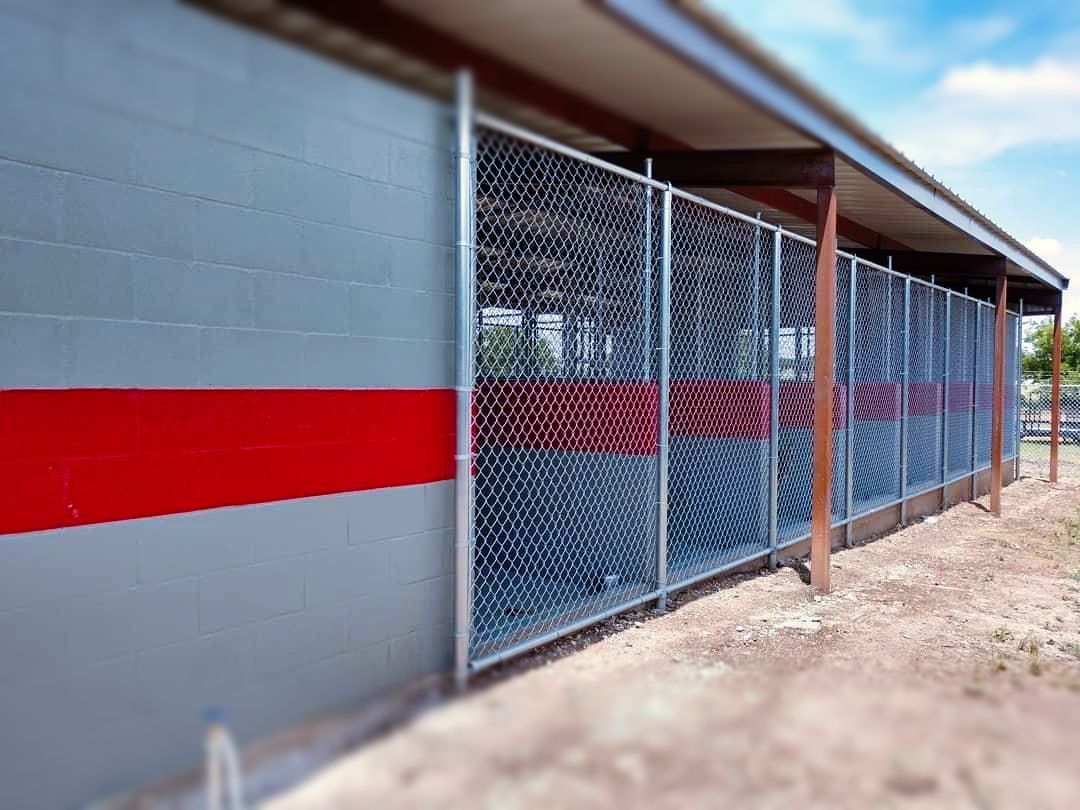 A chain link fence is surrounding a building with a red stripe on the side.