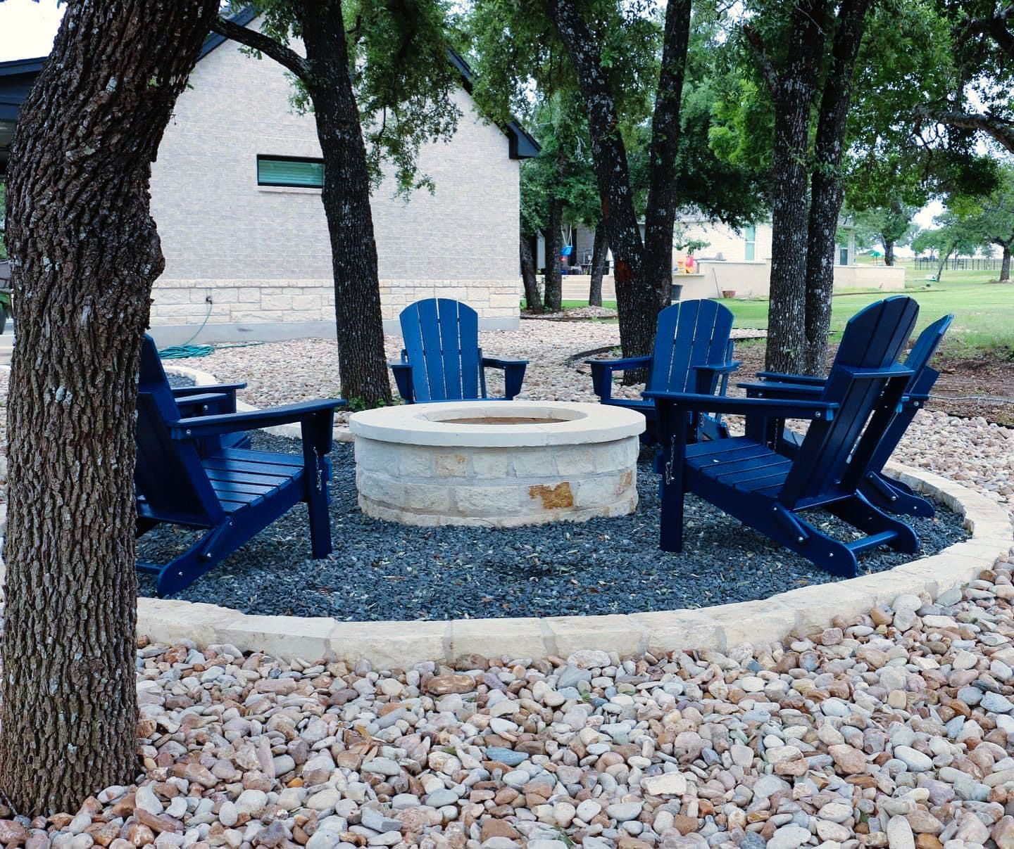 A fire pit with blue chairs around it
