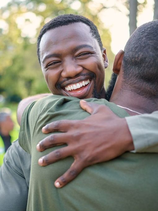 Two men wearing face masks are cooking food in a kitchen.