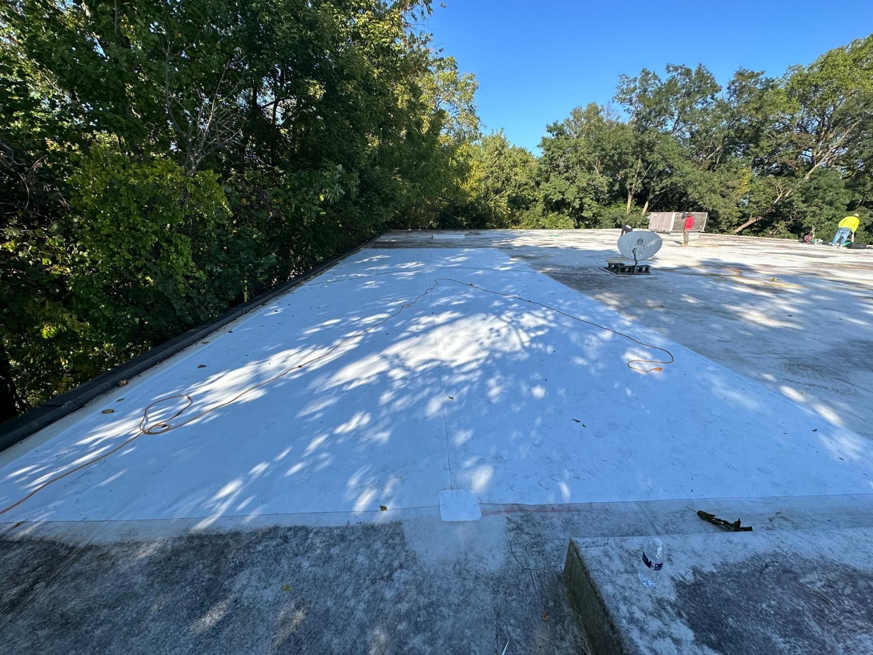 A white roof with trees in the background and a blue sky.