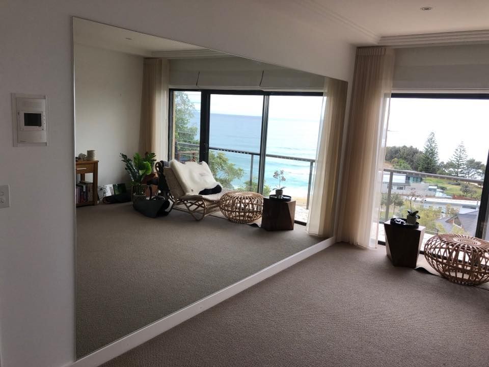 Spacious room with carpet, large mirror, and sliding glass doors overlooking a coastal view.