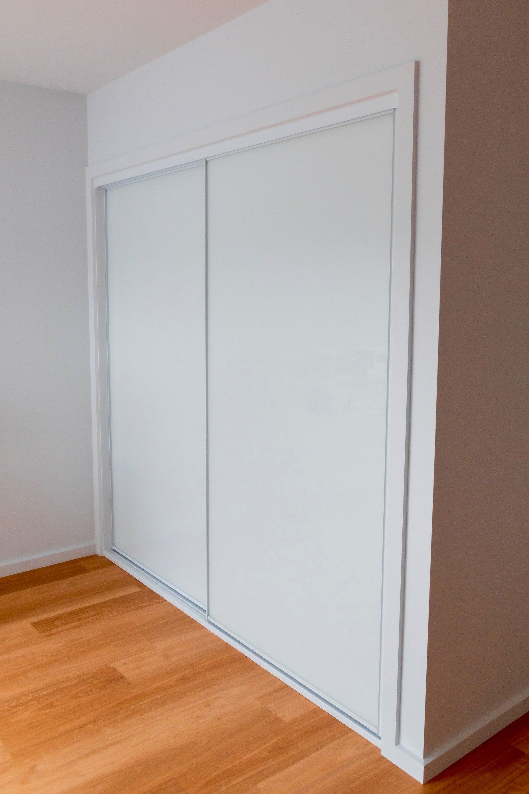 Sliding frosted glass closet doors beside a light wood floor