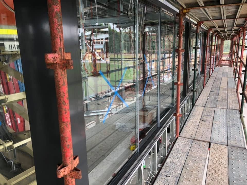 Scaffolding walkway beside glass wall inside an unfinished building