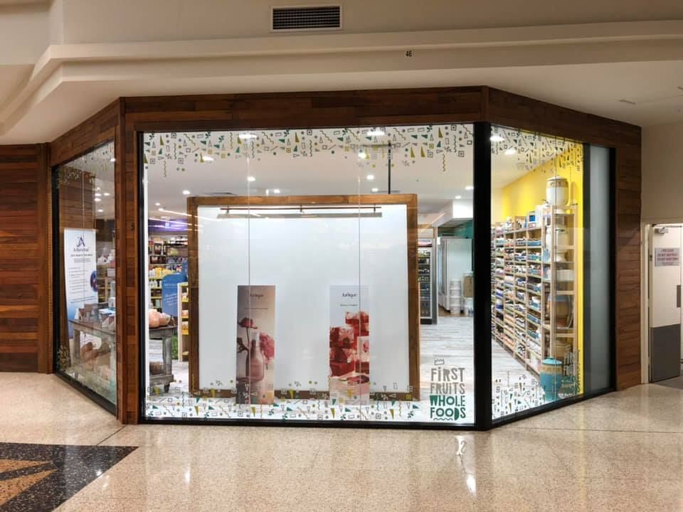 Closed storefront kiosk in a mall with white interior, glass display windows, and tiled floor section.