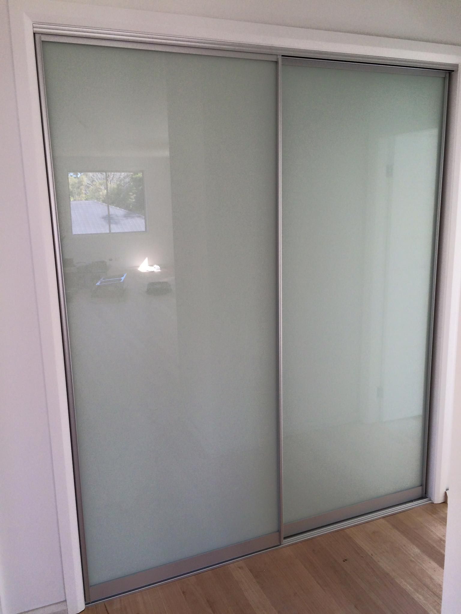 Sliding frosted glass closet doors beside a light wood floor