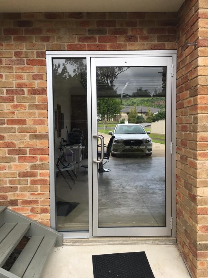 Sliding glass patio door framed by brick, reflecting a car in the wet driveway outside.