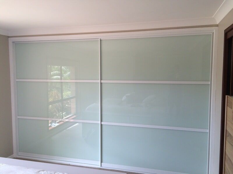 Frosted glass sliding closet doors with white trim in a bedroom