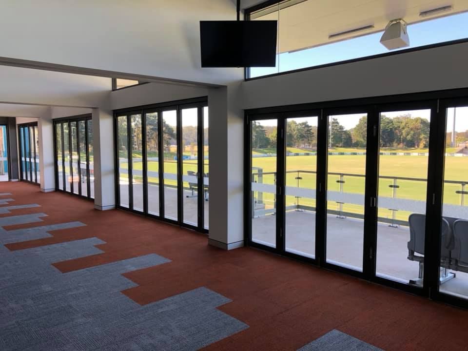 Covered walkway with large glass doors overlooking a grassy field