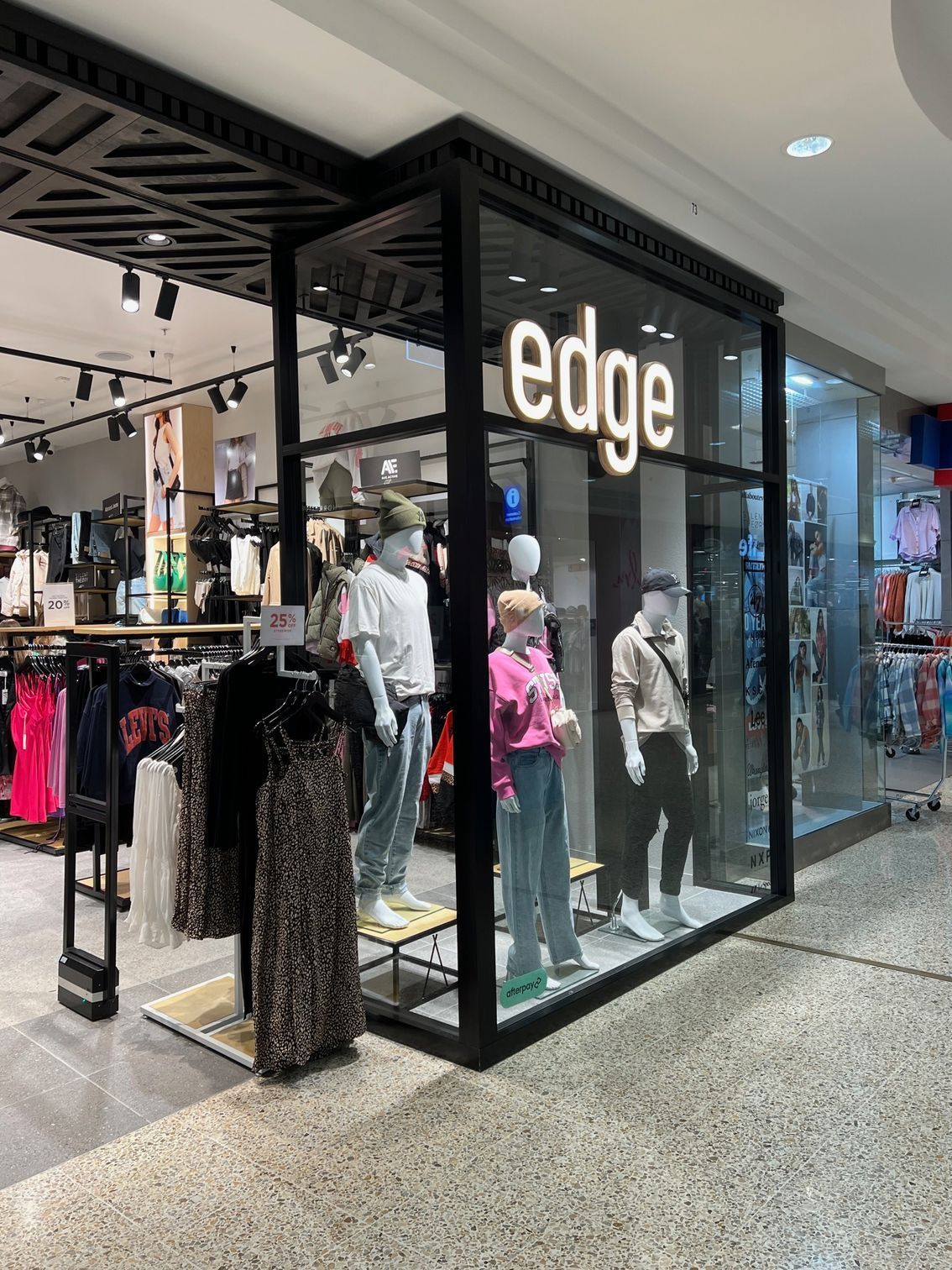 Clothing store storefront with mannequins in the window and a large “edge” sign.