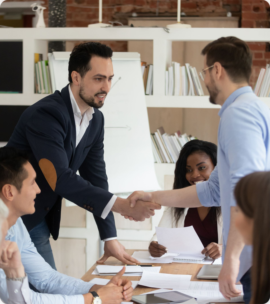 Business meeting with a handshake between two men in a modern office setting.