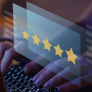 Hands typing on a backlit keyboard behind a transparent graphic displaying five gold stars, symbolizing a customer review.