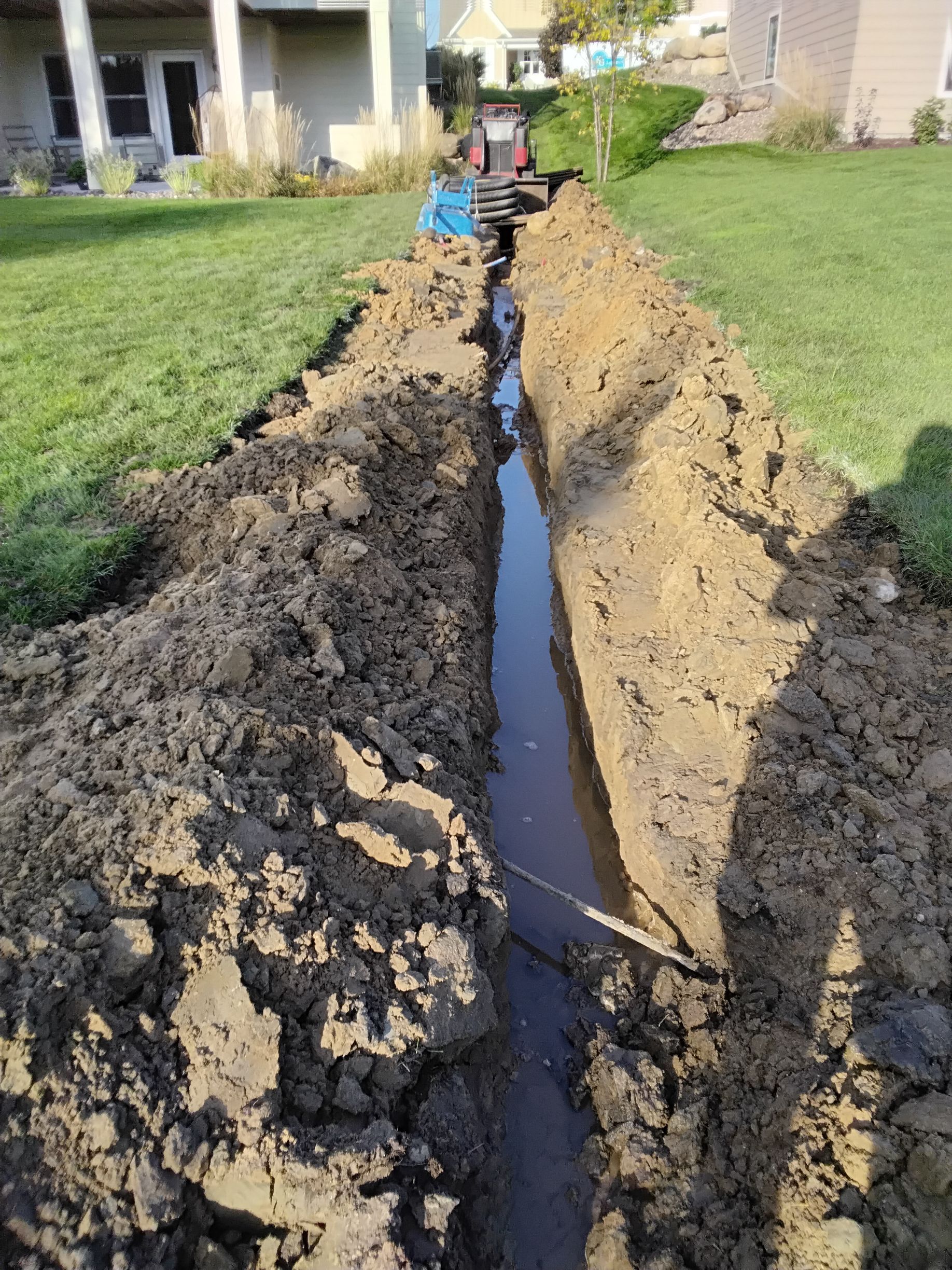 Trench for new French drain installation already starting to drain water from saturated wet clay soil