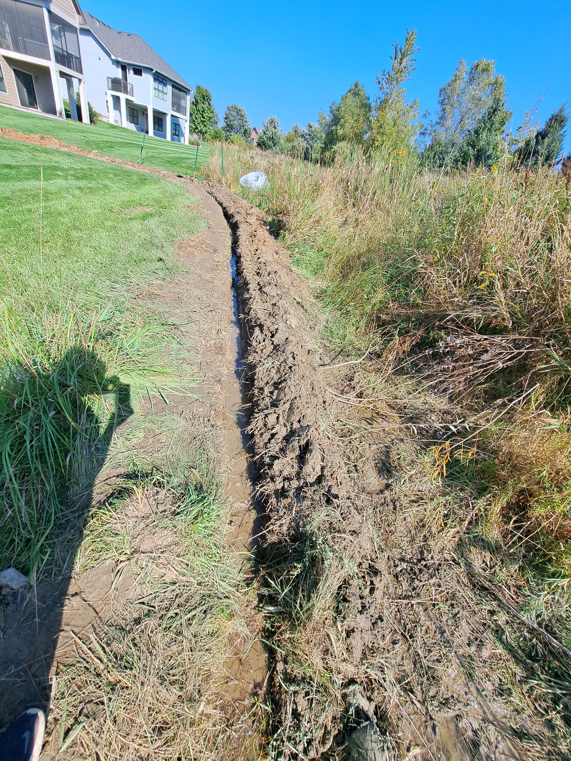 During photo of water draining out of French drain trenching during installation