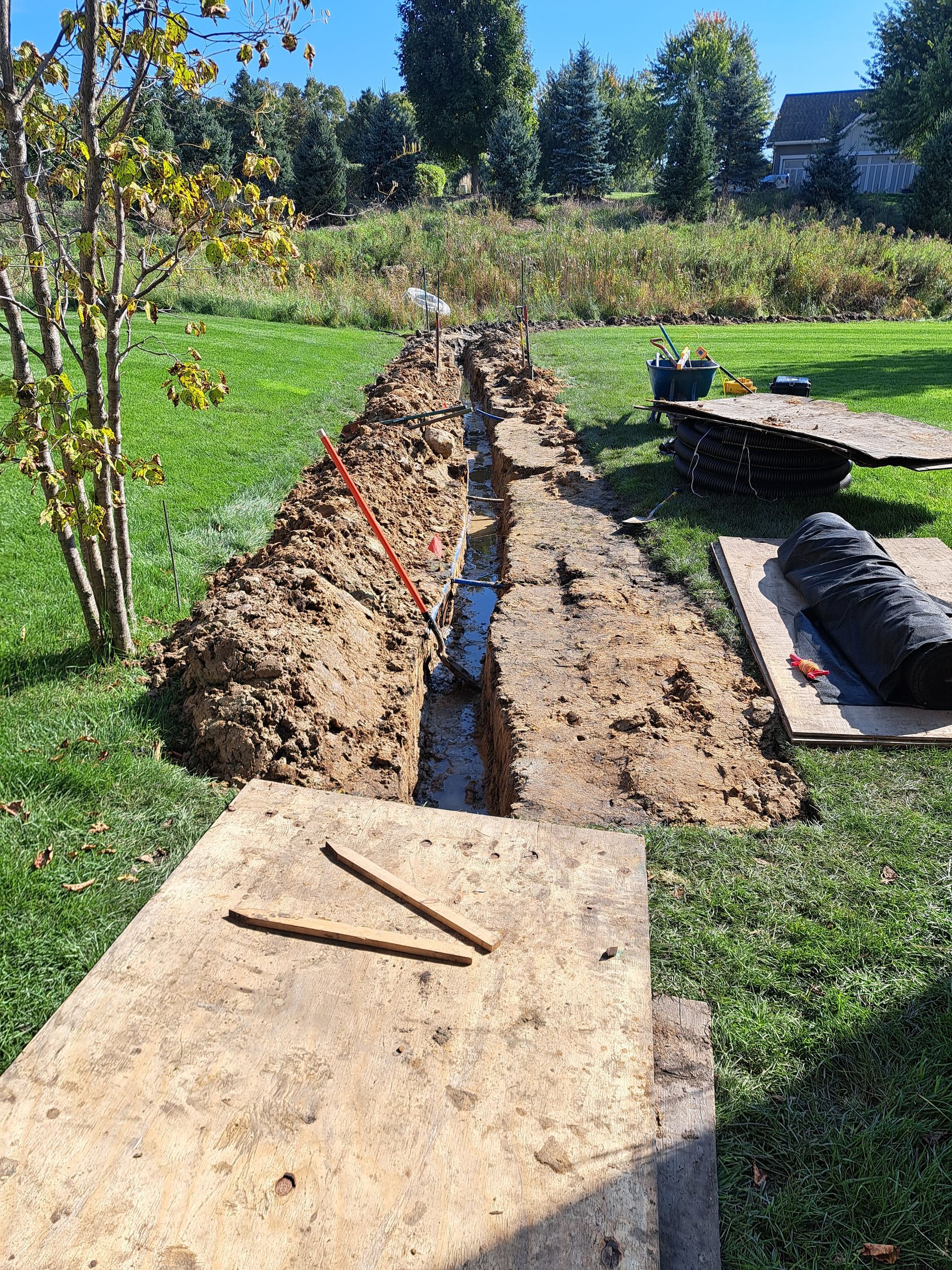 trench+for+new+french+drain+in+lawn+with+running+water+showing+it+works+irrigation+lines+crossing+trench