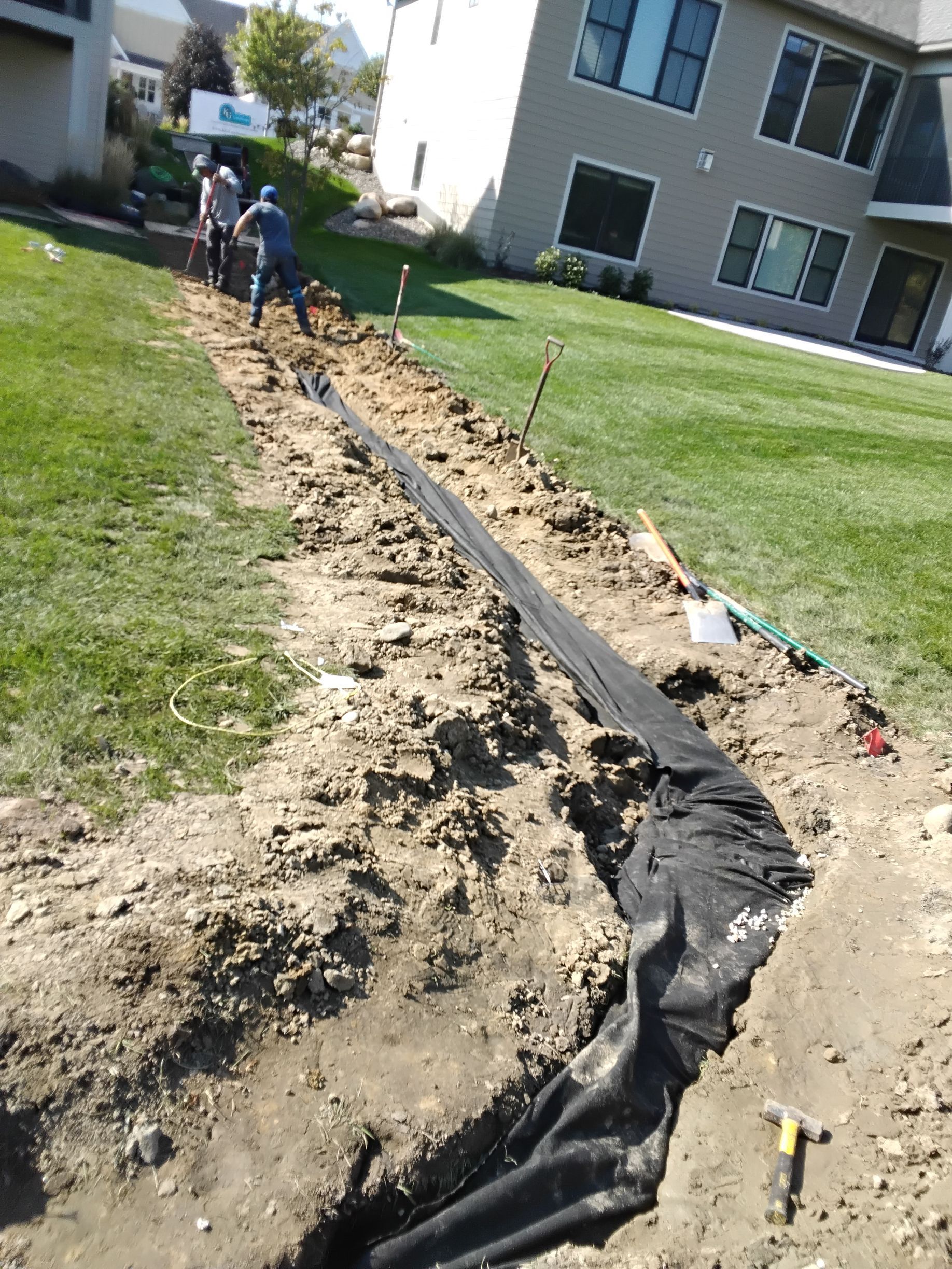 During pic of our crew wrapping filtration fabric over the top of the French drain rock and pipe to ensure it doesn't clog 