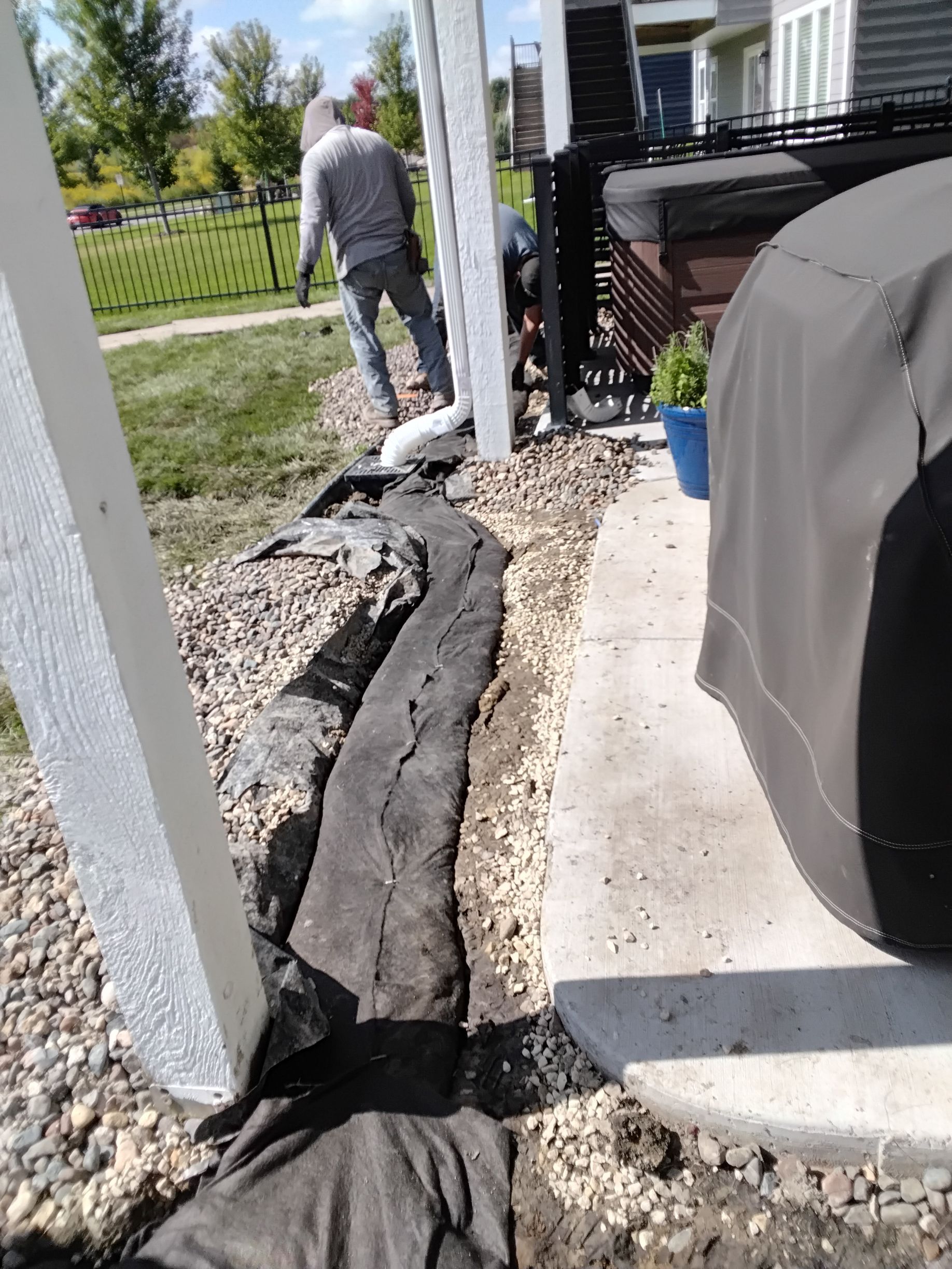 KG Landscape crew wrapping fabric around a French drain being installed around a patio  in Plymouth MN 