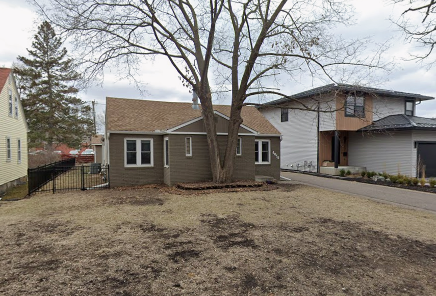 A tall tree is planted very close to a house.