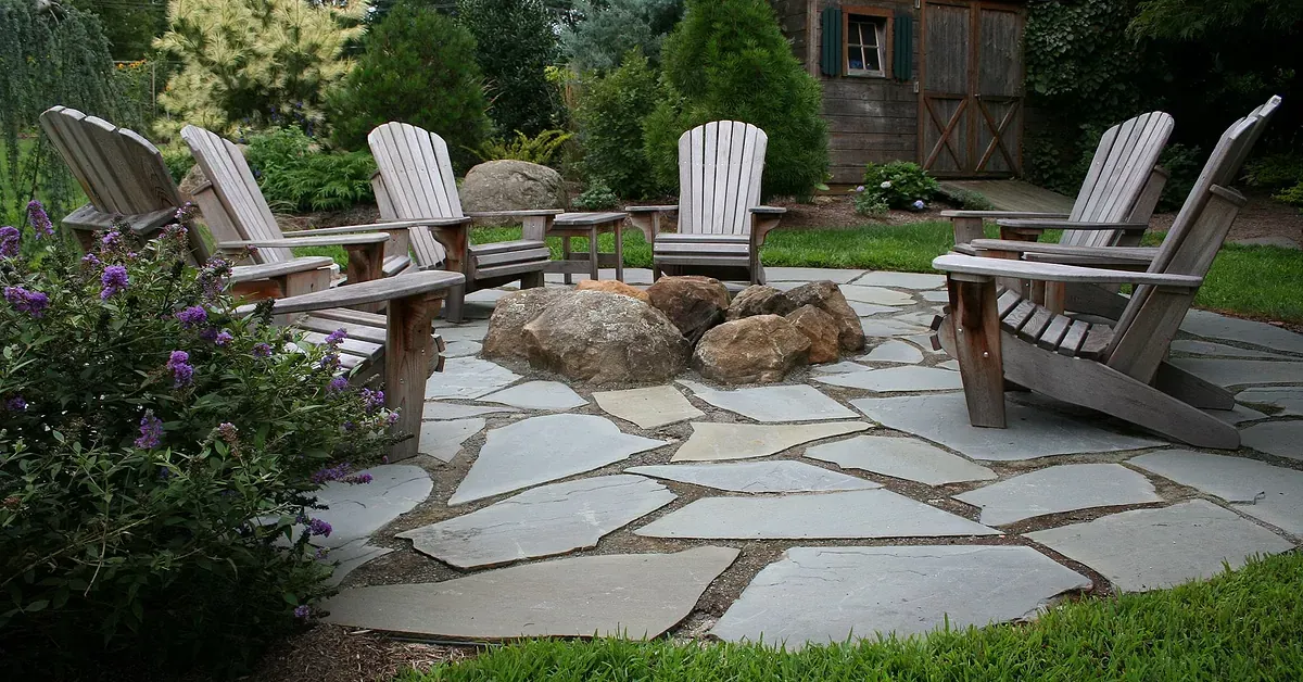 flagstone patio natural looking with a boulder fire pit inside of patio and Adirondack Charis MN 