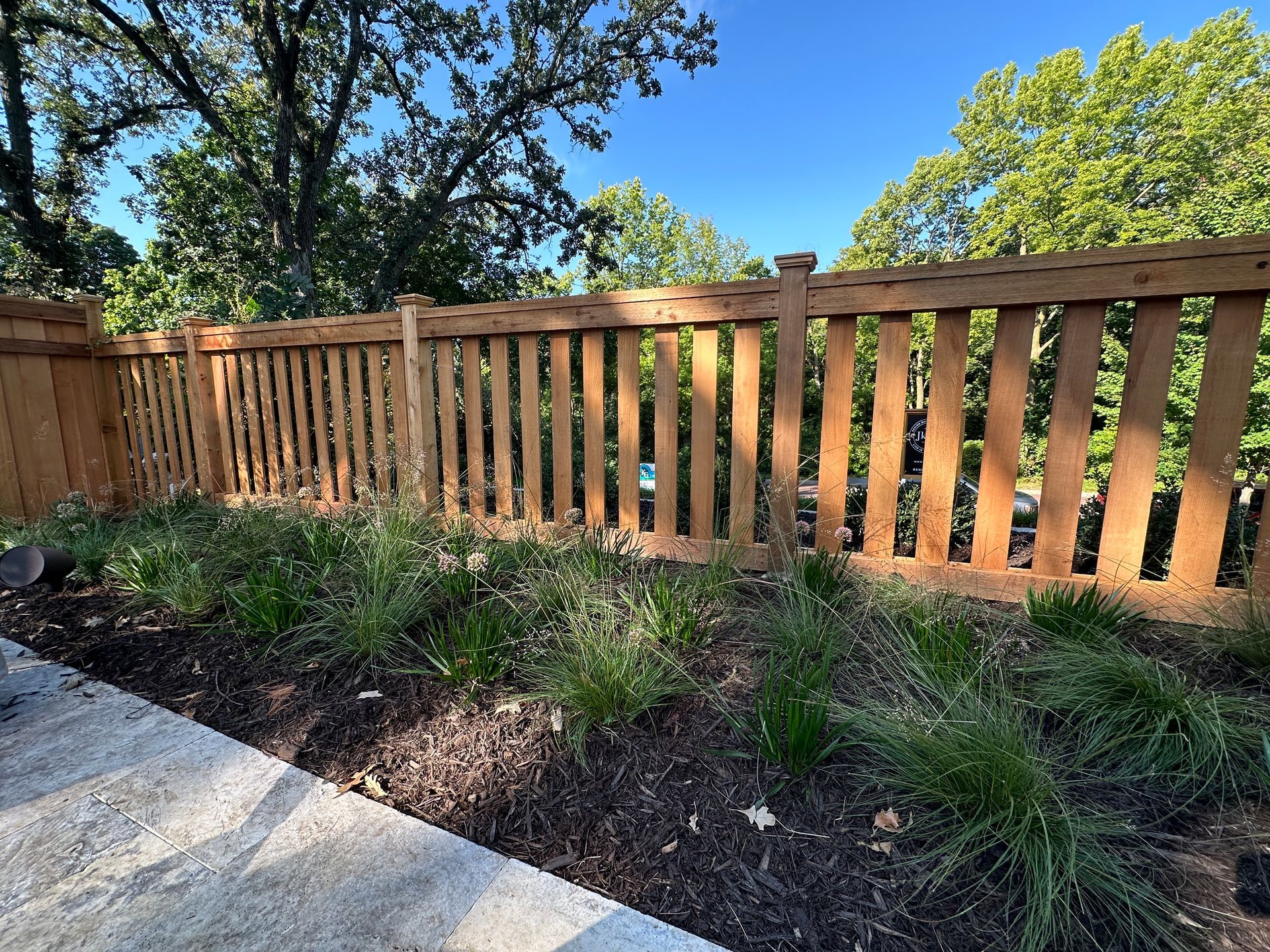 Cedar+picket+fencing+with+allium+and+praire+dropseed+perennials+mulch+overlooking+Minnehaha+creek+in+Minneapolis+MN
